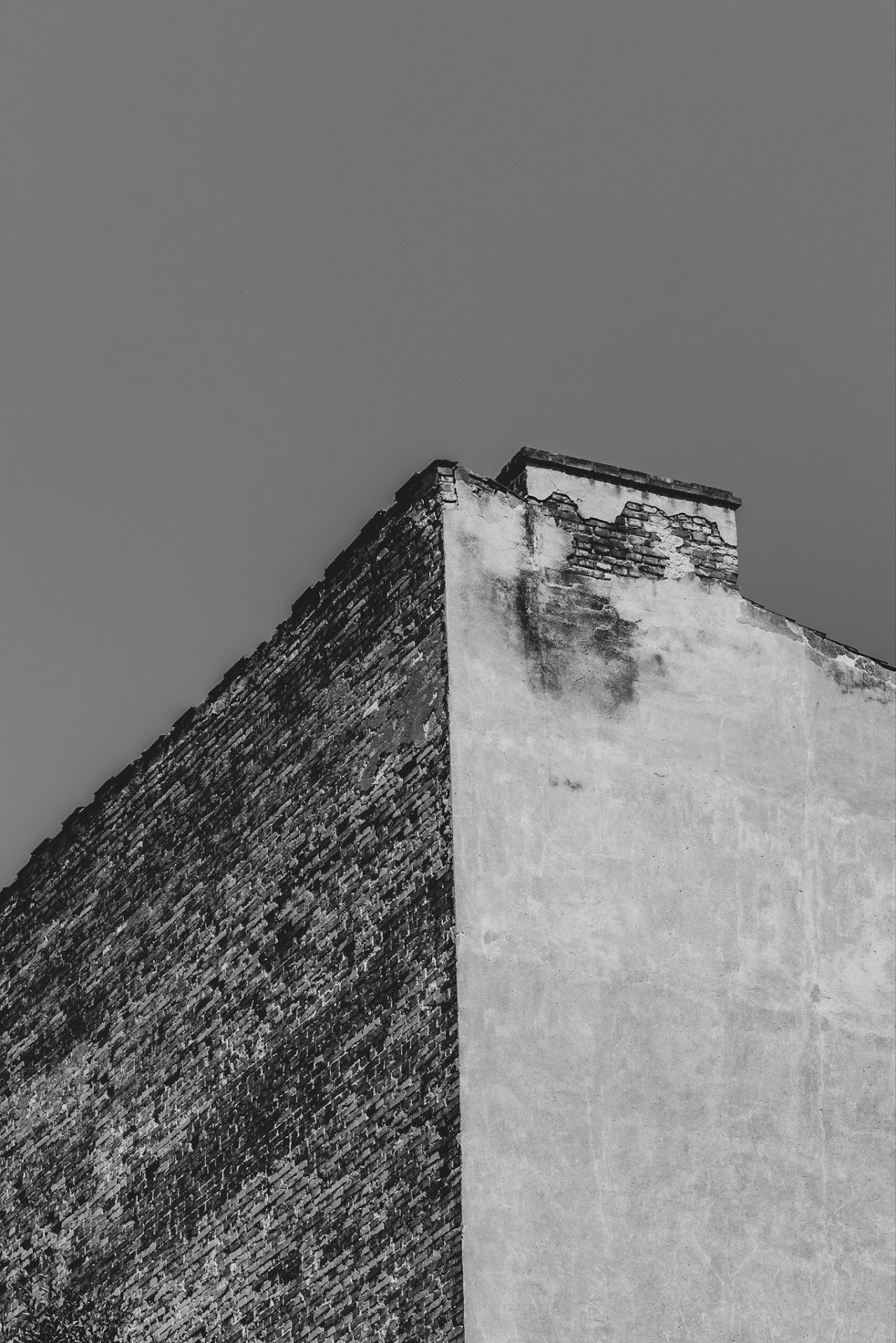 Monochrome worn concrete corner against a blank gray sky