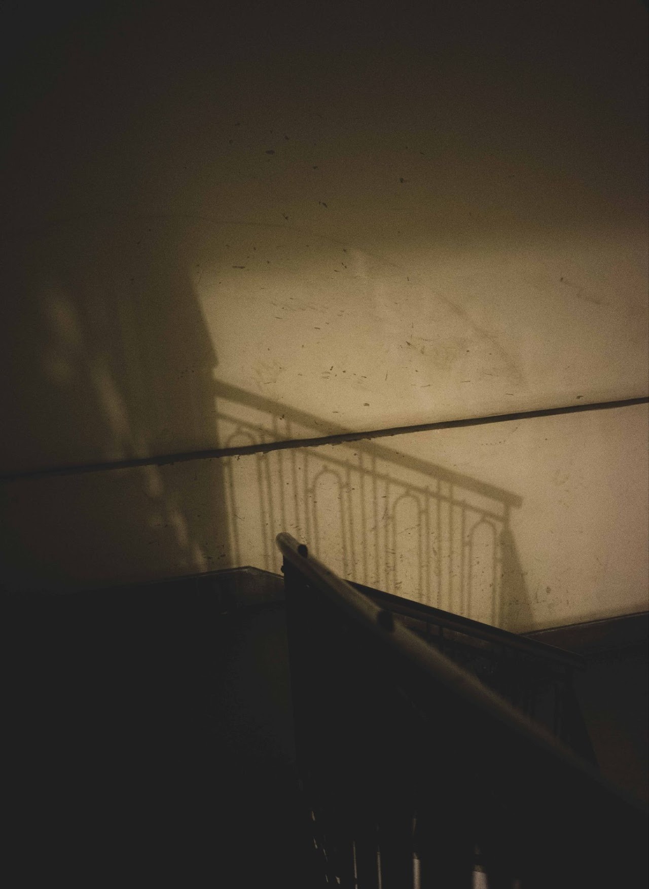 Dim stairwell shadow with railing and warm wall light