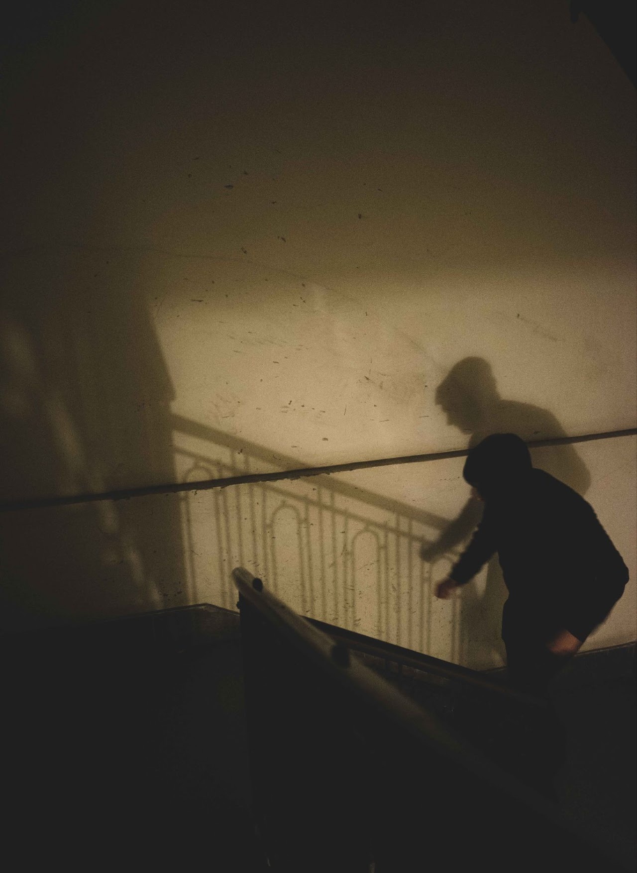 Silhouetted figure climbing stairs through warm shadowed light
