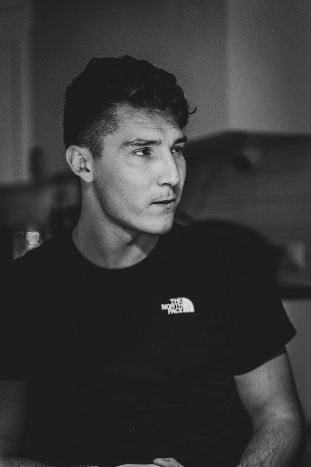 Monochrome young man in a dark shirt looking sideways indoors