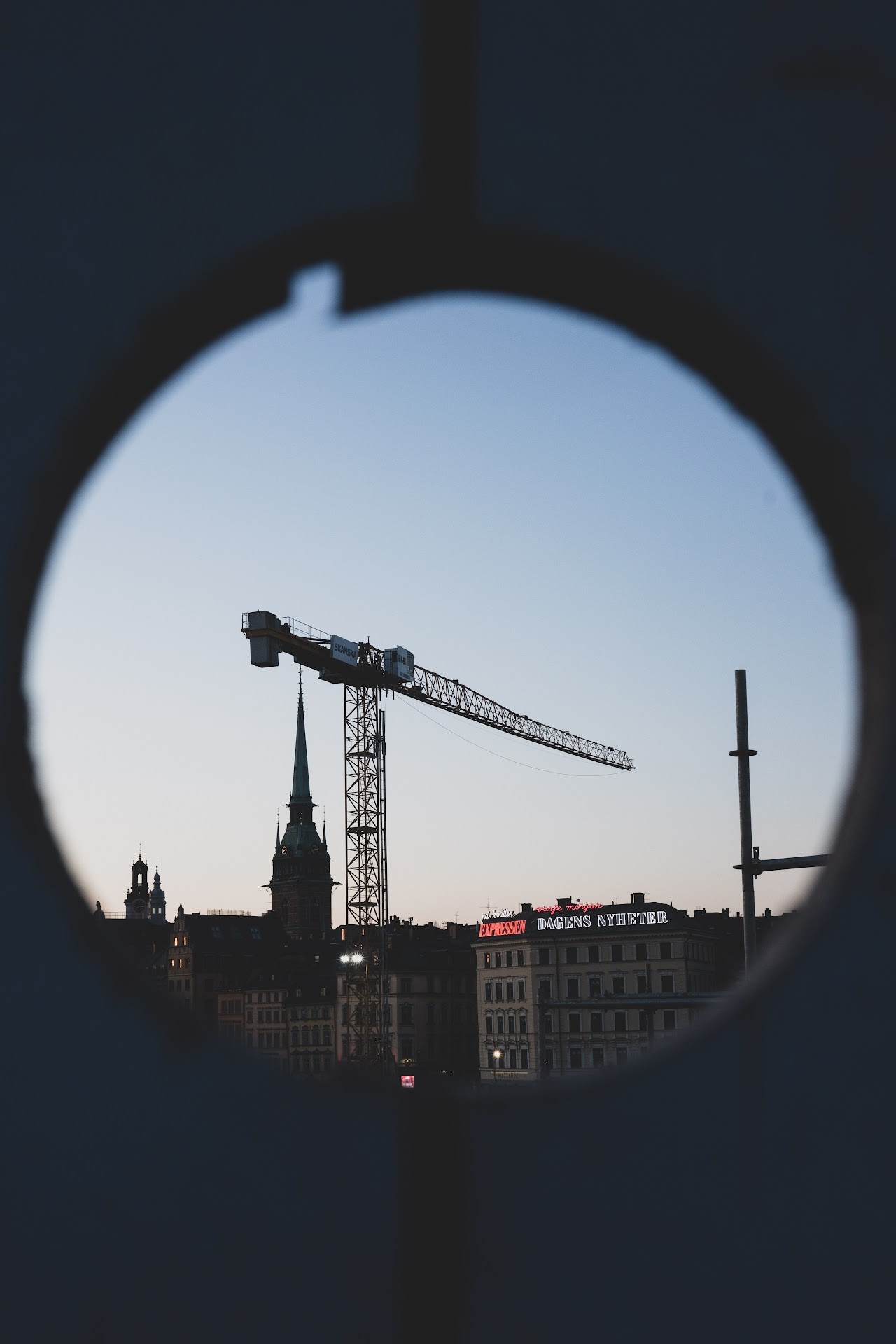 Crane and Stockholm skyline viewed through a circular opening