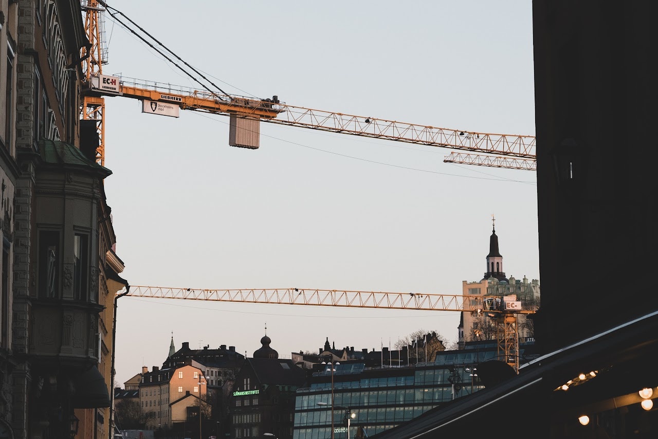 Slussen construction cranes crossing above Stockholm rooftops at dusk