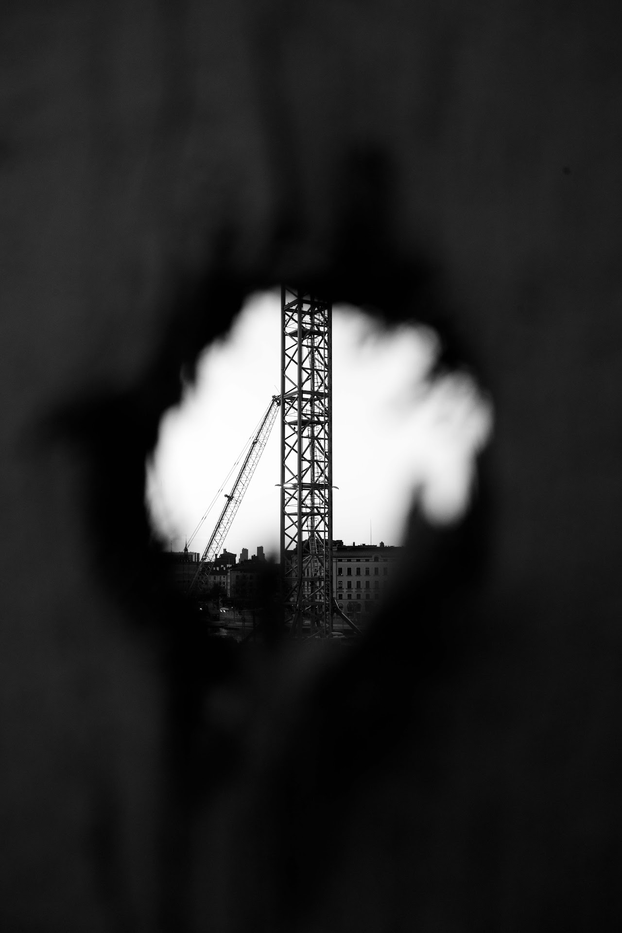 Crane framed through a torn opening in black and white
