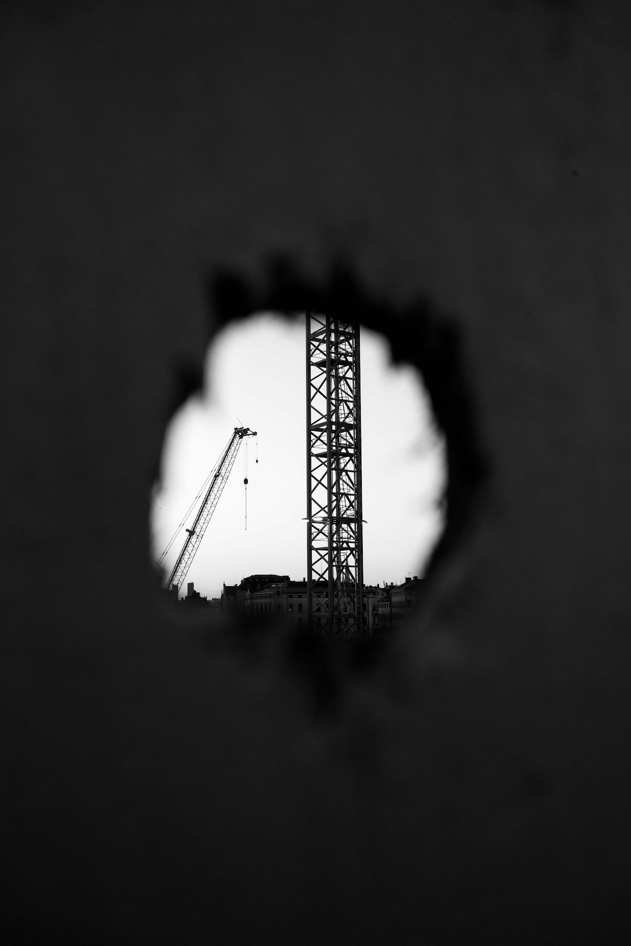 Crane mast seen through a small torn hole