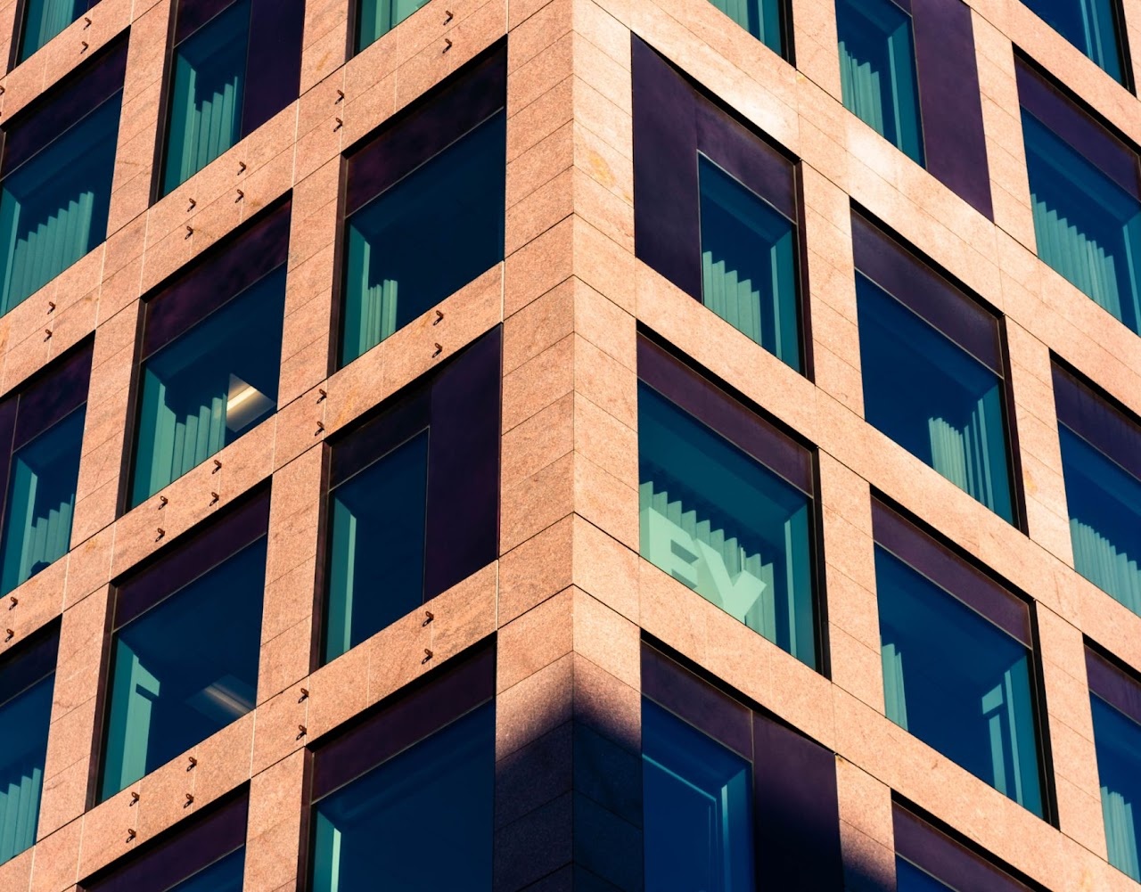 Sunlit orange stone corner facade with teal window glass