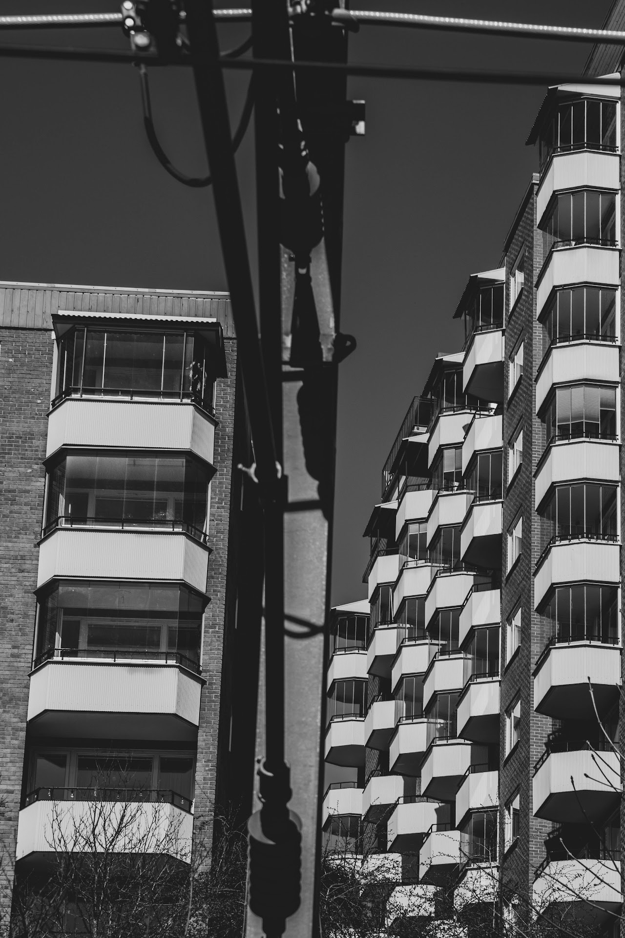 Monochrome balconies, utility poles, and wires between tall buildings