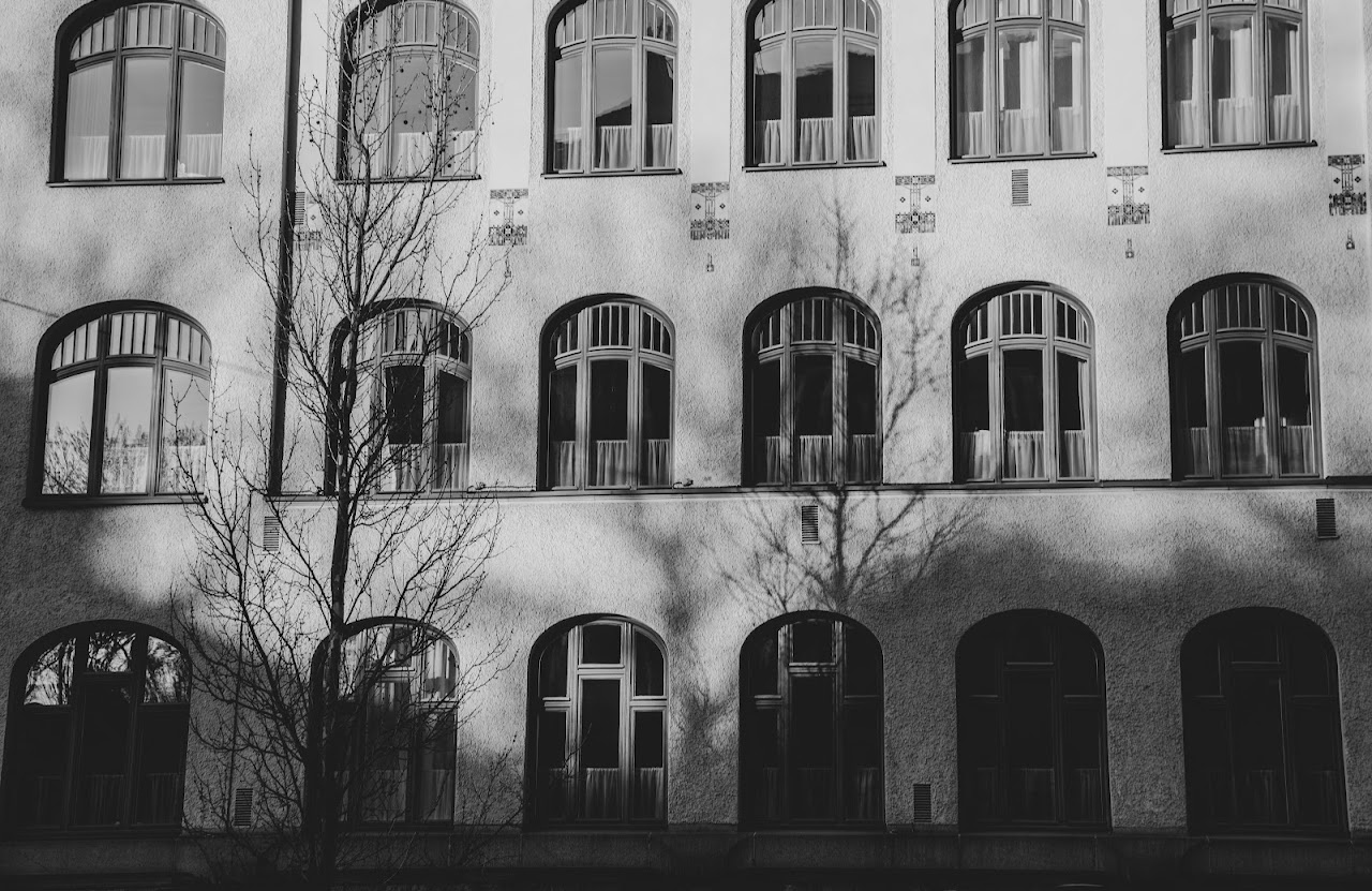 Monochrome facade with arched windows and a bare tree