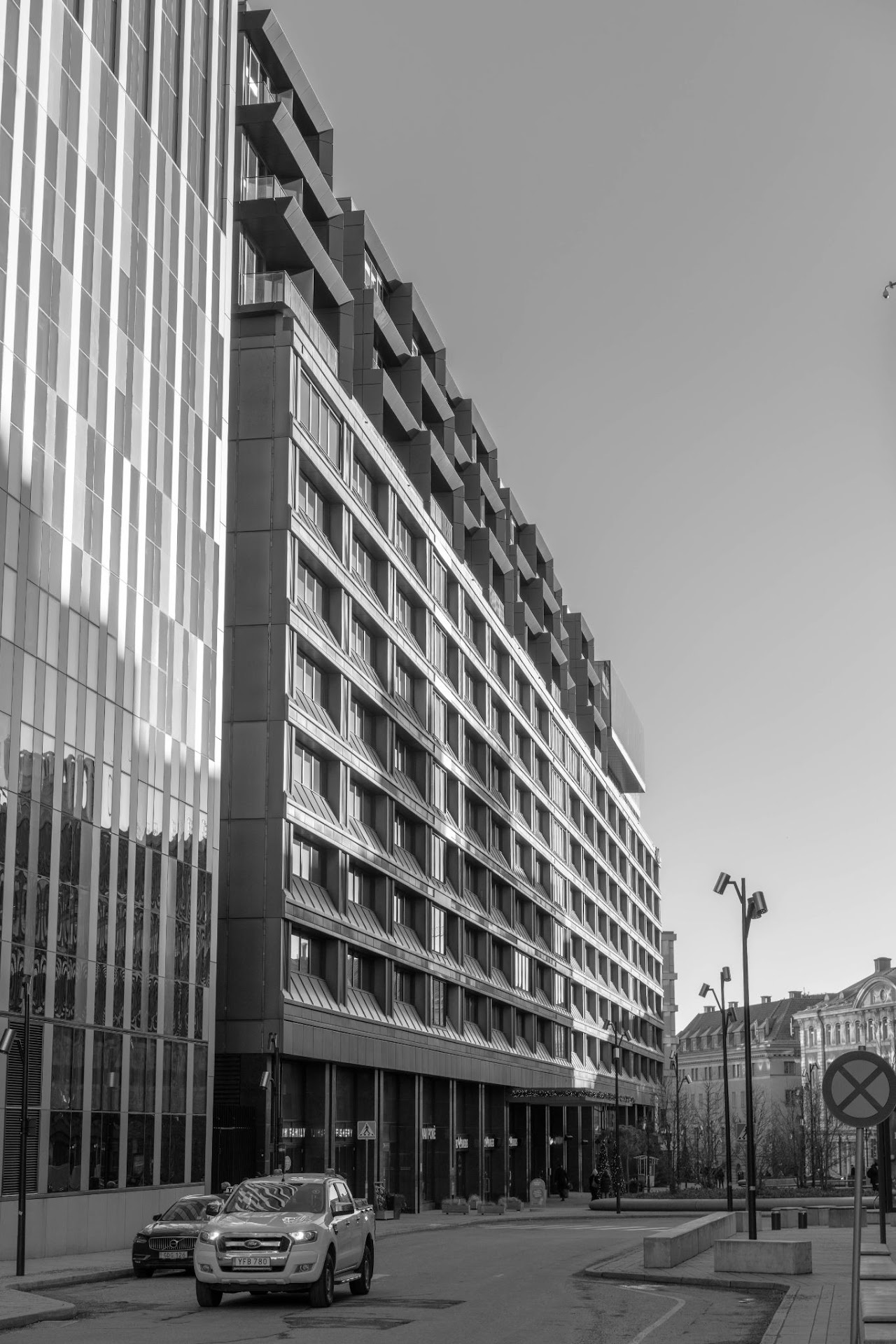 Monochrome city street beside a long modern glass facade