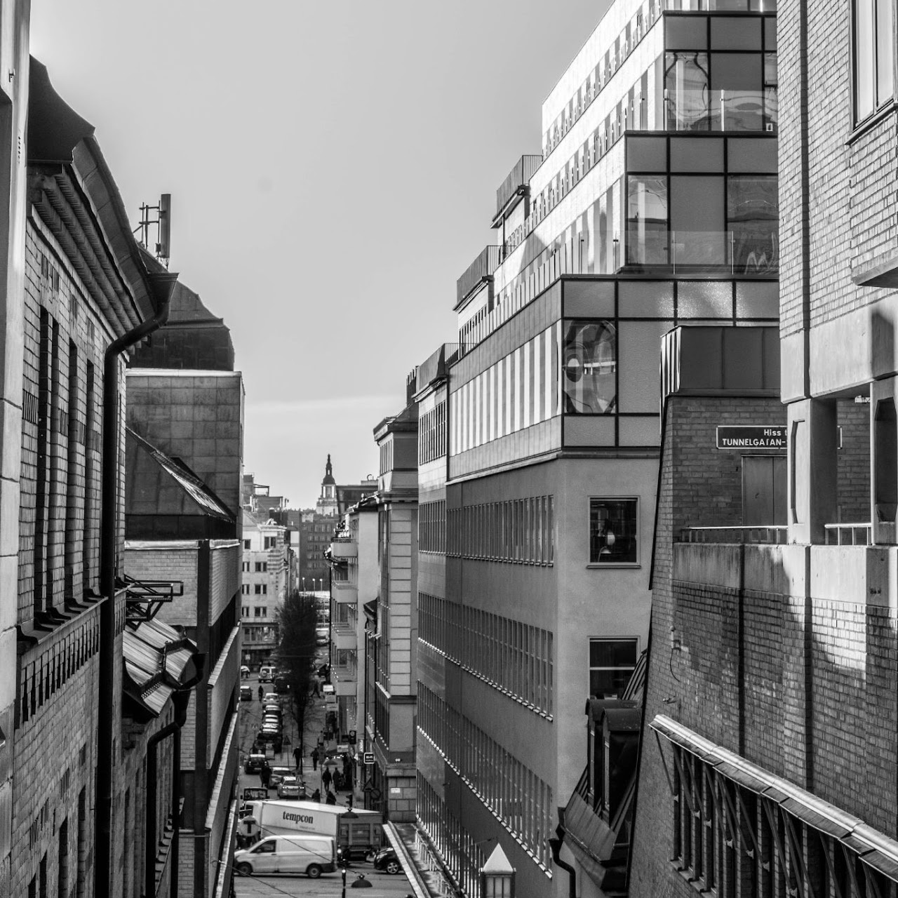 Monochrome stairway descending between dense city buildings