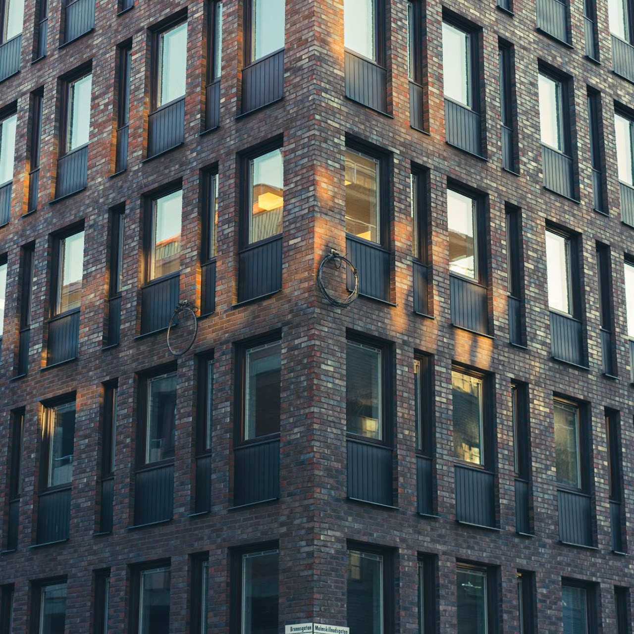 Brick corner building with warm lit windows at dusk